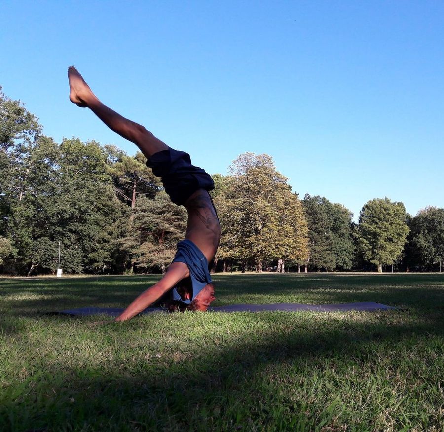 Basile Pagliardini en posture inversée de Hatha Yoga dans un parc